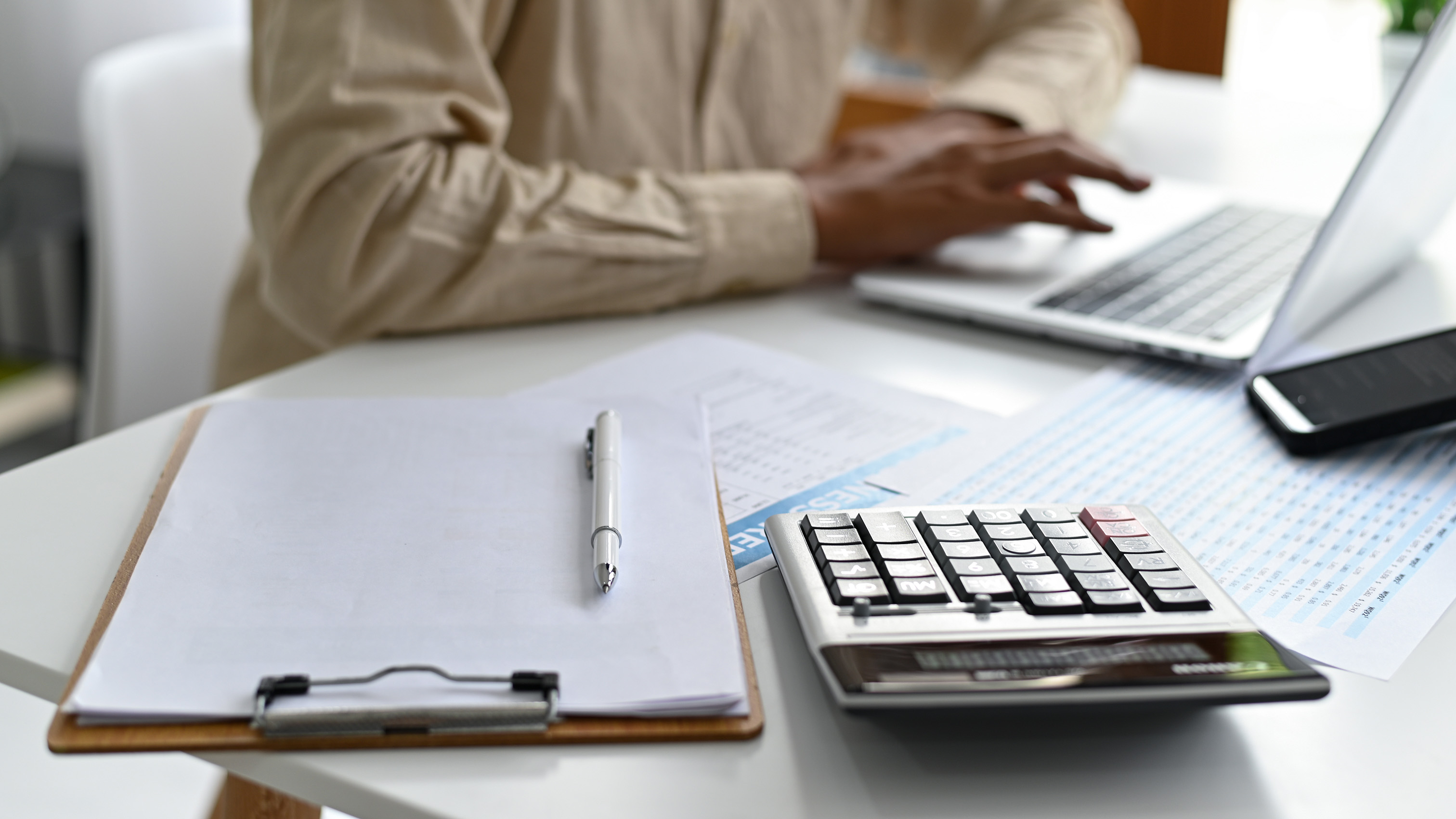 clipboard and calculator on desk with people